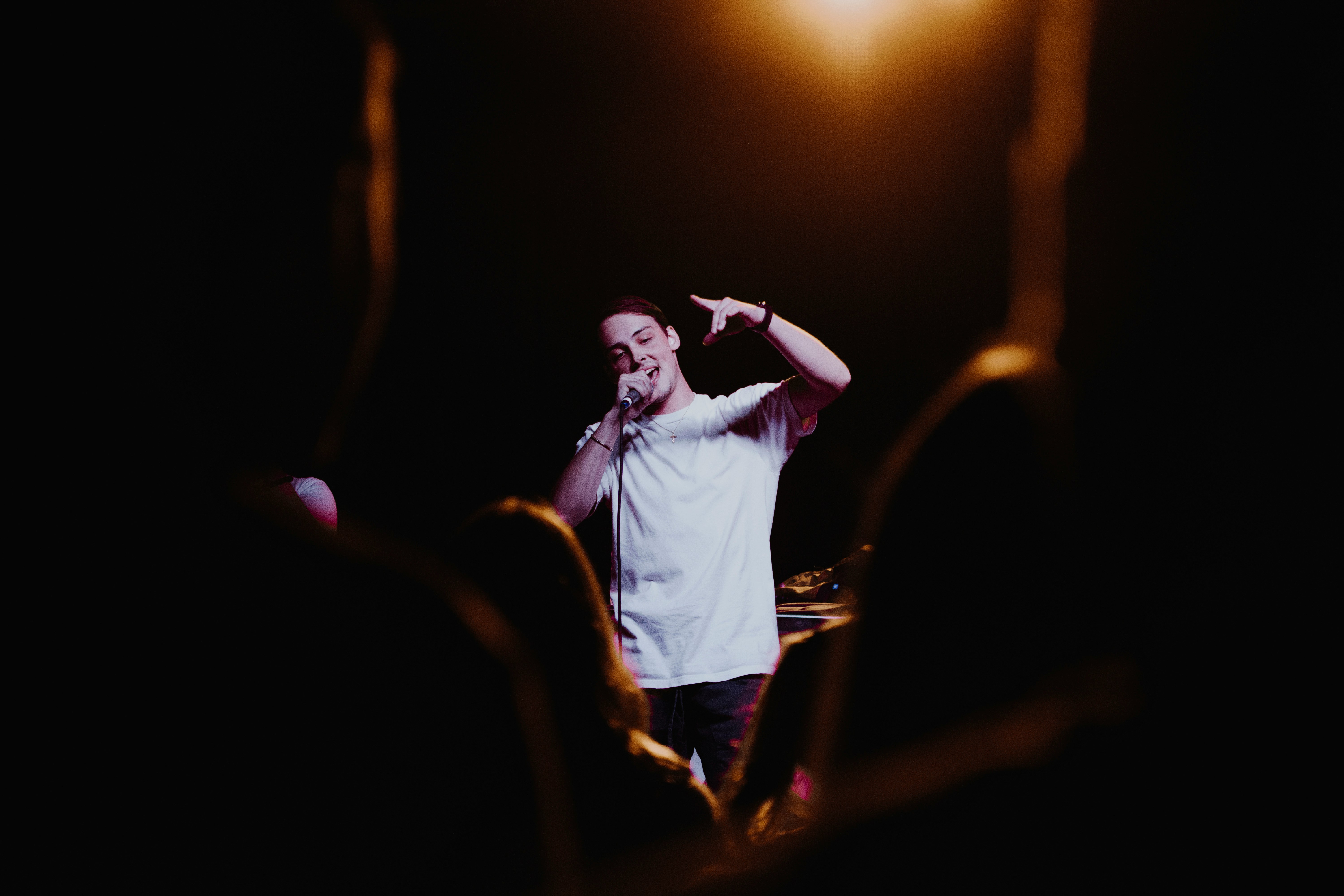 A live performer seen through the audience at a dark venue